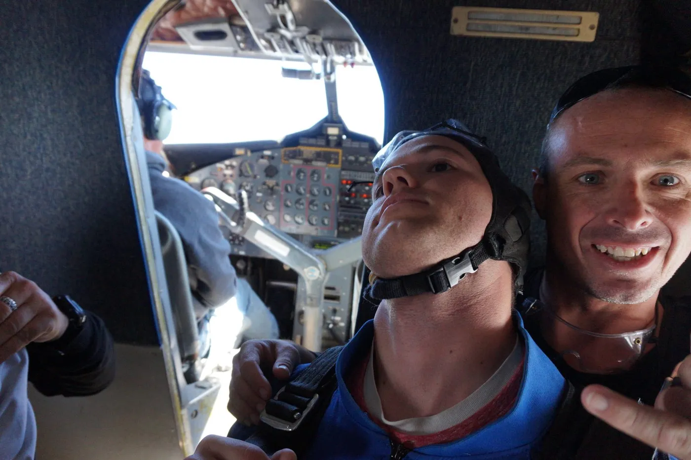 Inside the skydiving plane on the climb to altitude, with the cockpit visible through the doorway behind us.