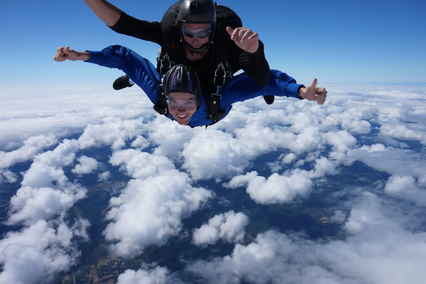 Freefalling in tandem with my instructor above the clouds, thumbs up and grinning.